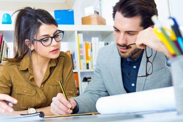 homem e mulher em um escritório com livros conversando sobre negócios e analisando documentos com papel e folha