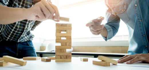 Dois homens tentando equilibrar uma torre com jogo de madeiras para não deixar cair