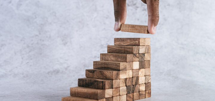 mão de homem negro incluindo o último degrau de uma escada de peças de madeira