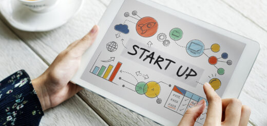 mão de homem branco segurando um tablet com um Plano de Fundo com texto "START UP" e diversas imagens de inovação ao redor do texto