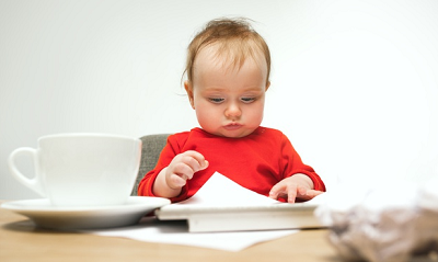 criança vestindo uma roupa vermelha esentada à mesa com um prato e uma folha